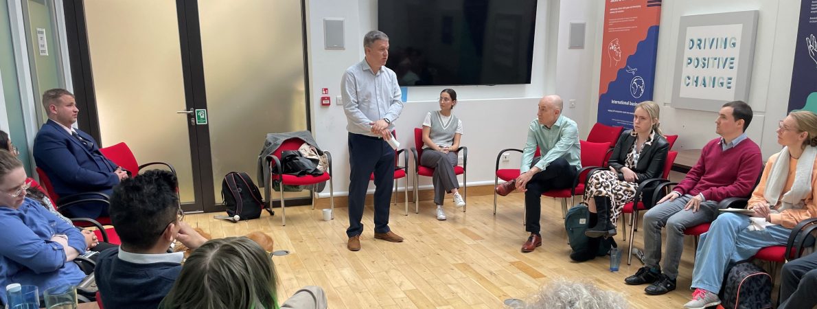 Image shows channel 4 skill share session taking place at the TPT hub. A man is stood in a meeting room, talking to a group of people sat in a semi-circle formation in front of him