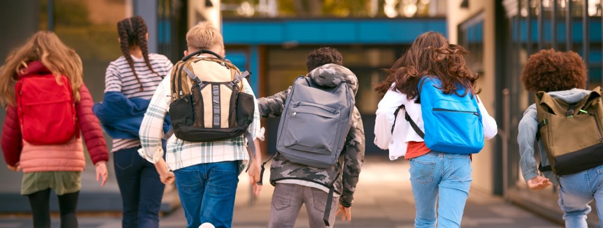 Group Of Secondary Or High School Pupils Running Away From Camera Outside School Building