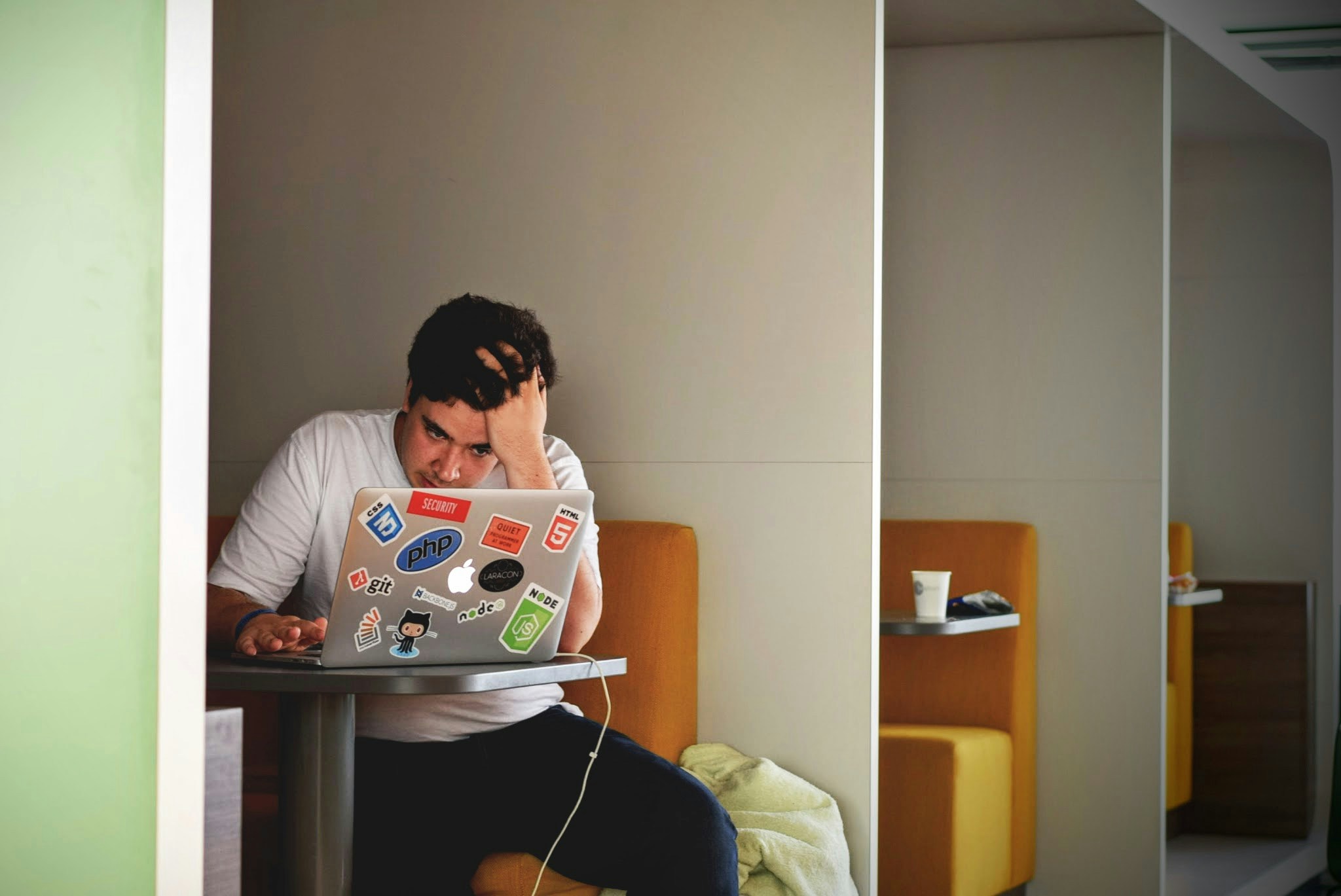 A student sat at their laptop. The student is looking stressed and has one hand in their hair. 