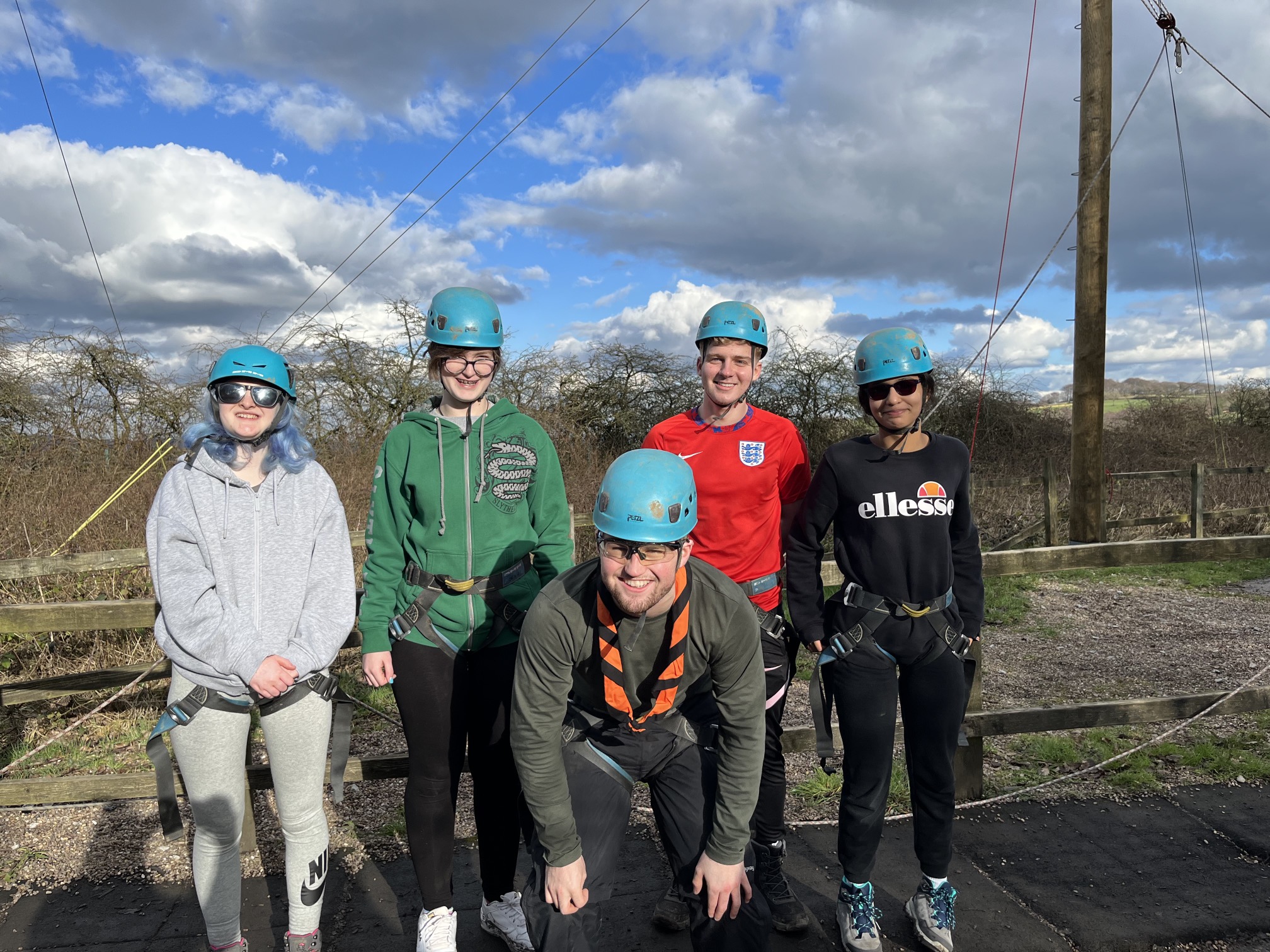 Five students in helmets and harness stood looking and smiling at the camera. 3G swing structure in the background.