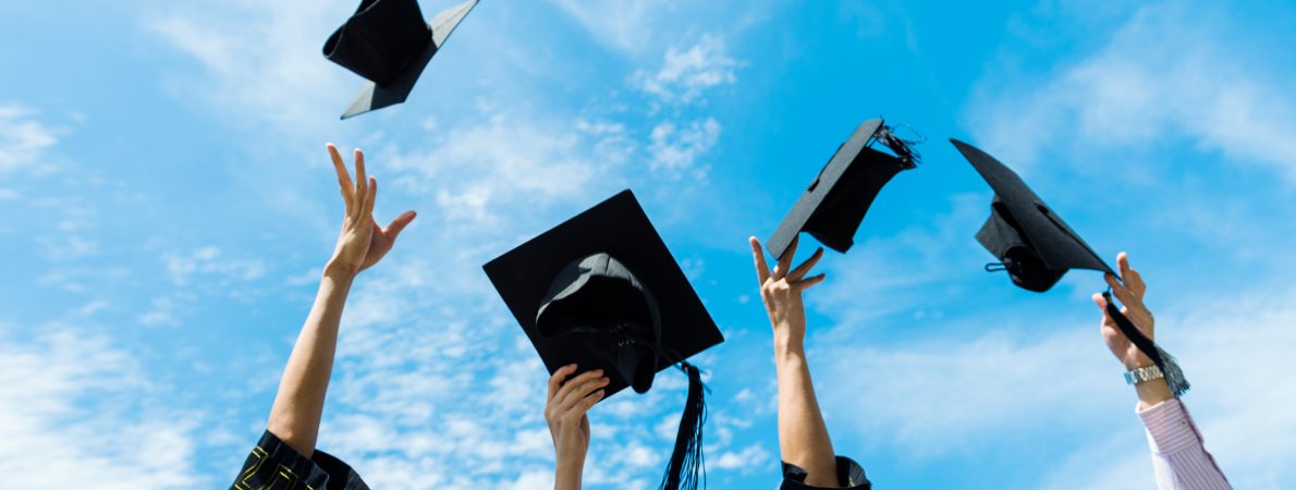 A picture of some graduation hats being thrown into the air, agaisnt a bright blue sky.