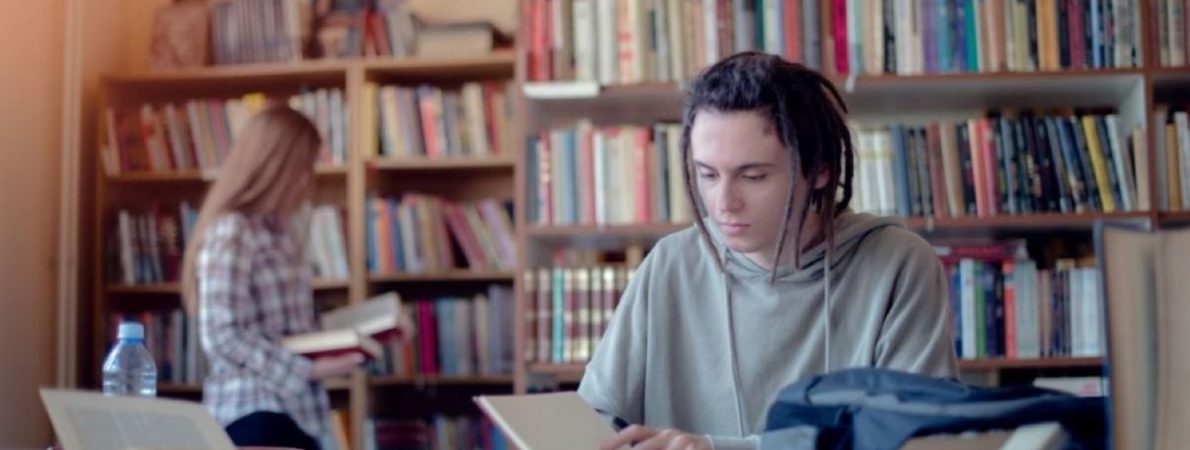 A picture of a student in a library, with pen and paper in front of her, ready to take notes on all the services available in this resource.