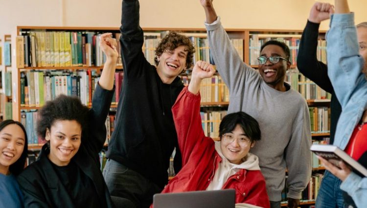 a university library with books and laptops open on the table in front of them.