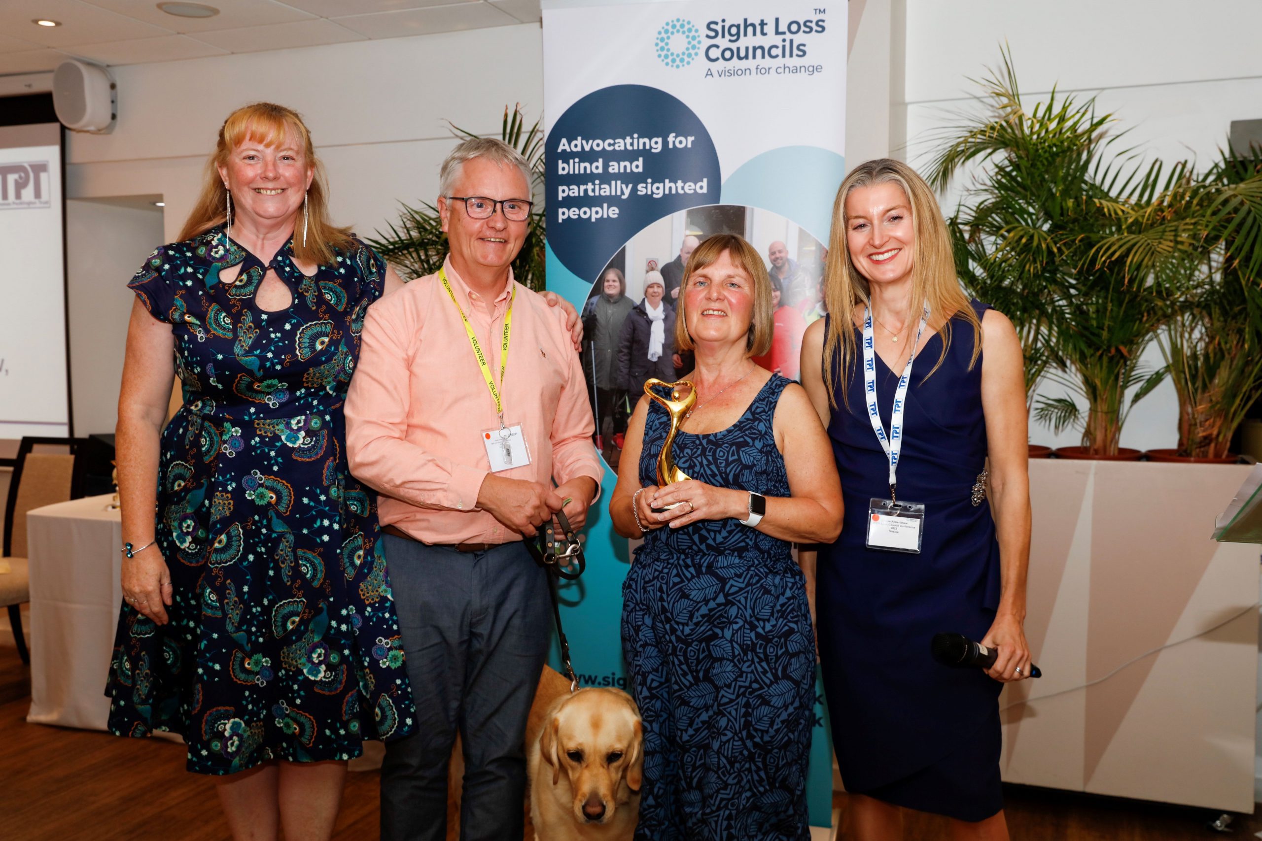 Tricia Sail, Stuart & Julie Stephens Gloucestershire SLC, guide dog Heidi, and Louise Robertshaw, Trustee at TPT. Julie is holding her award for individual of the year at the Rodney Powell Awards.